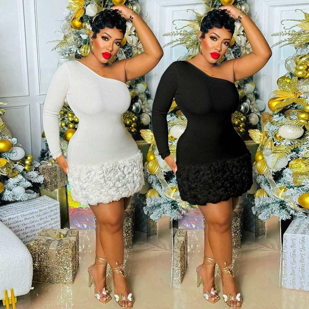 Woman wearing one-shoulder mini dress in black and white, floral hem, holiday background