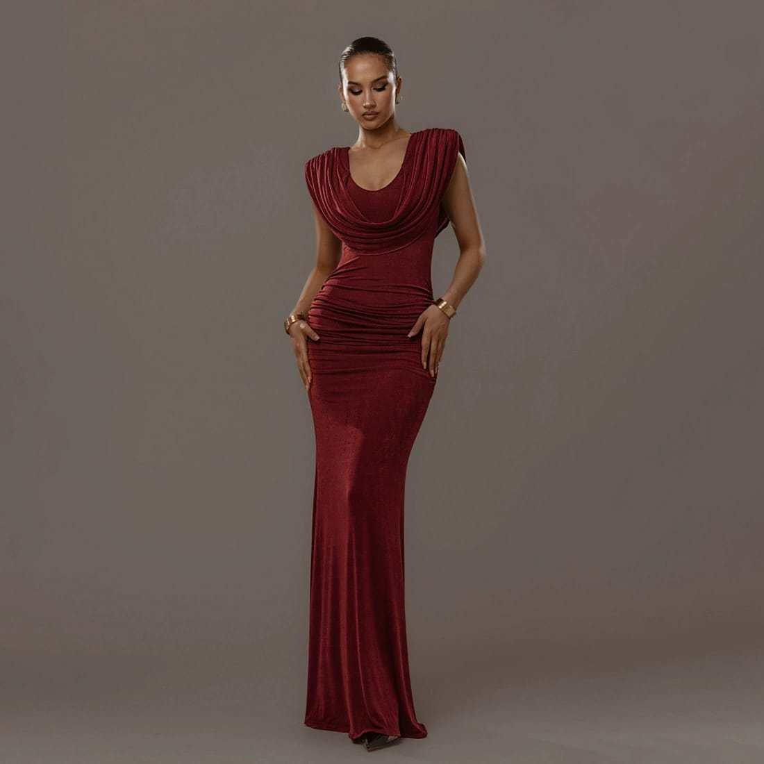 Woman in elegant burgundy evening gown with draped neckline, posing on neutral background