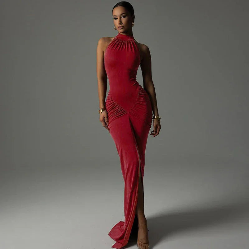 Woman in red velvet halter neck evening gown with ruched details and front slit