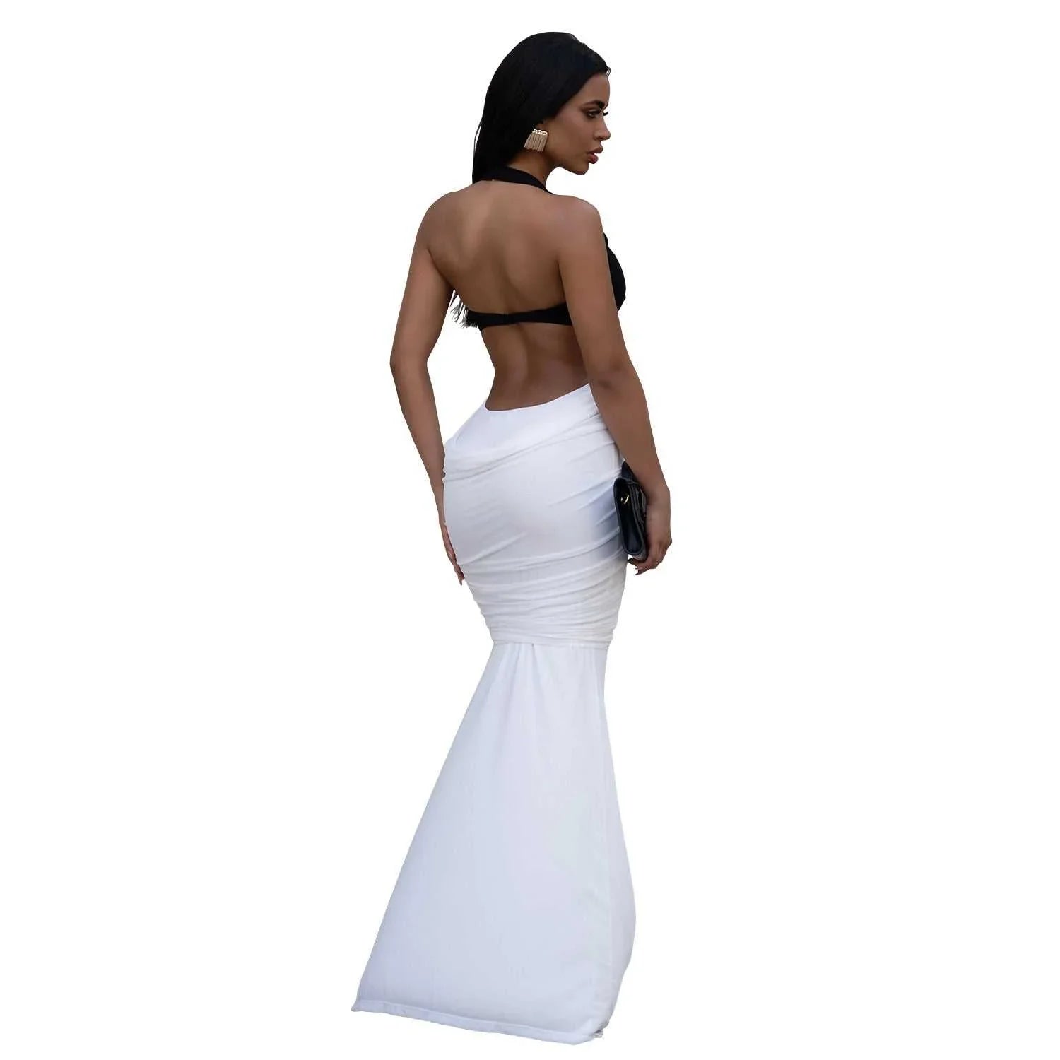 Woman in a backless black halter top and high-waisted white mermaid skirt, holding clutch