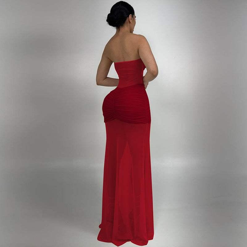 Woman wearing a strapless, ruched red evening gown with sheer skirt, standing in studio