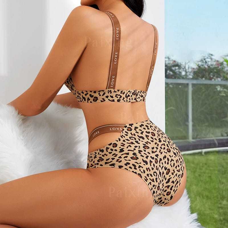 Woman wearing leopard print high-waisted bikini with LOVE strap detailing, sitting indoors
