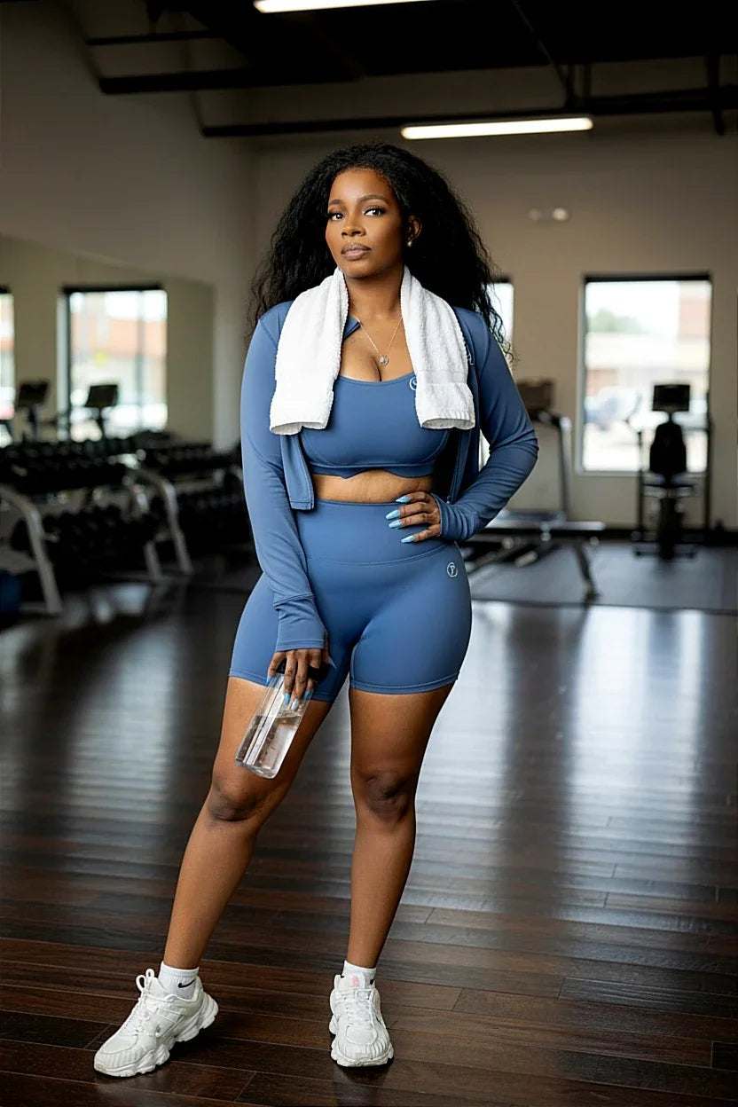Woman in blue athletic set with towel and water bottle in gym setting