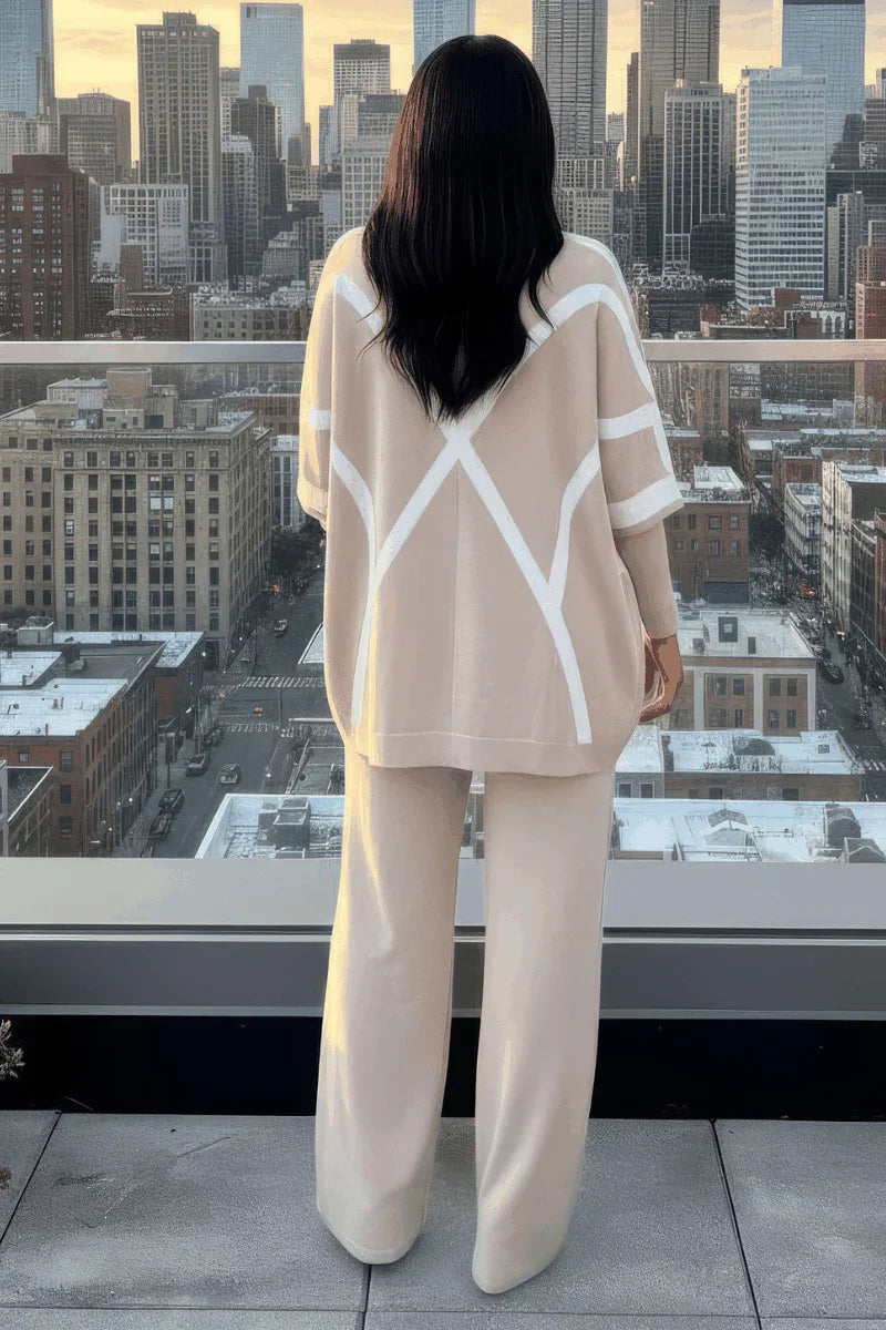 Woman in beige lounge set with white geometric stripes standing on rooftop with city view