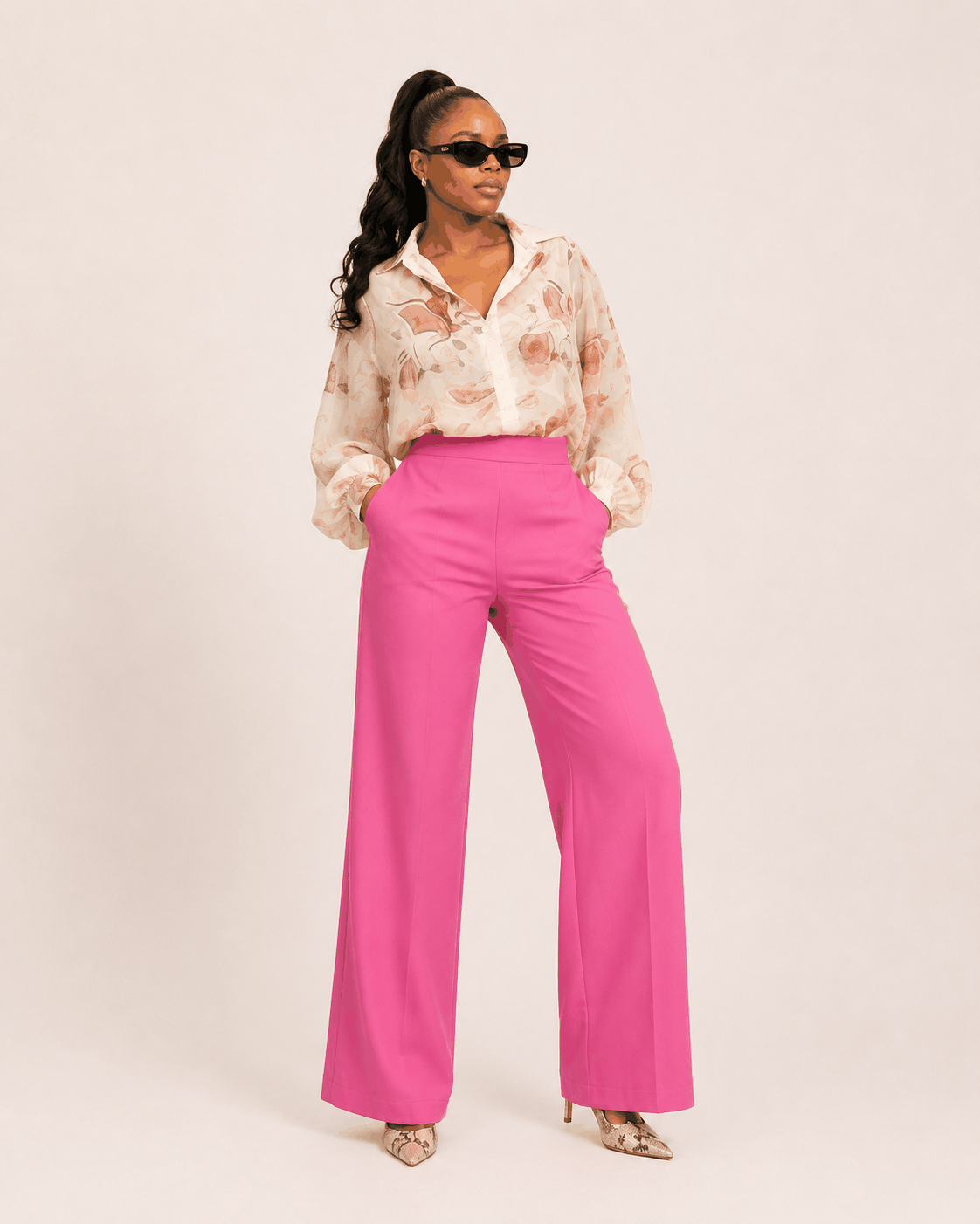 Woman wearing a blush pink tailored formal sweatsuit with a fitted shirt and bootleg pants, showcasing modern elegance and polished style for office and formal occasions